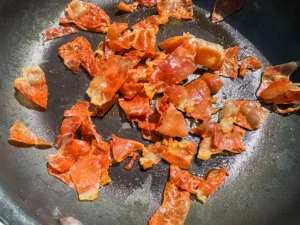 prosciutto cooking in skillet.