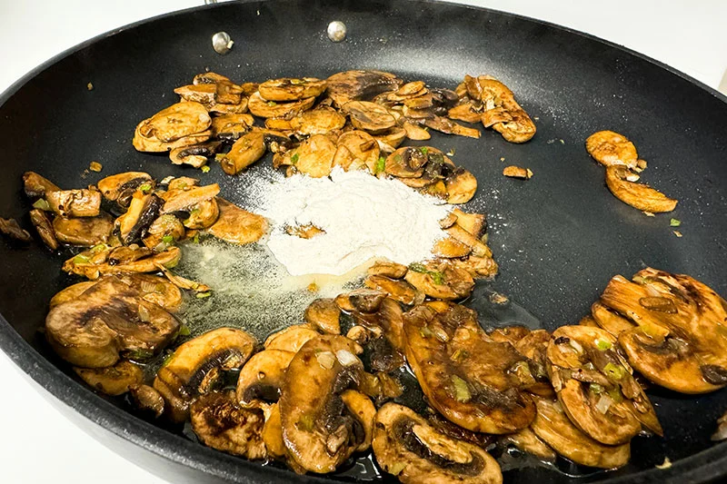 mushrooms and green onions cooking with roux in skillet.