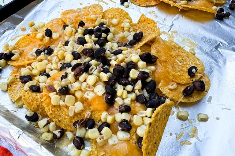 pile of tortilla chips, topped with beans, corn and cheese.