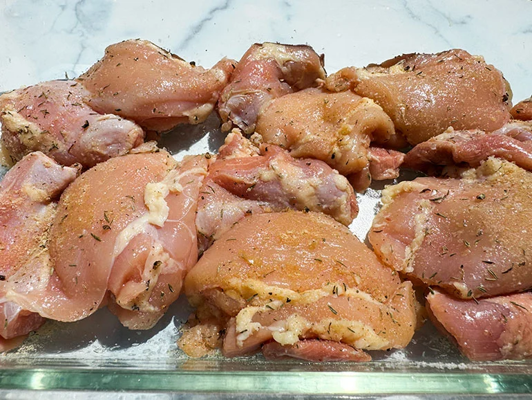 raw chicken with seasoning in a baking dish.