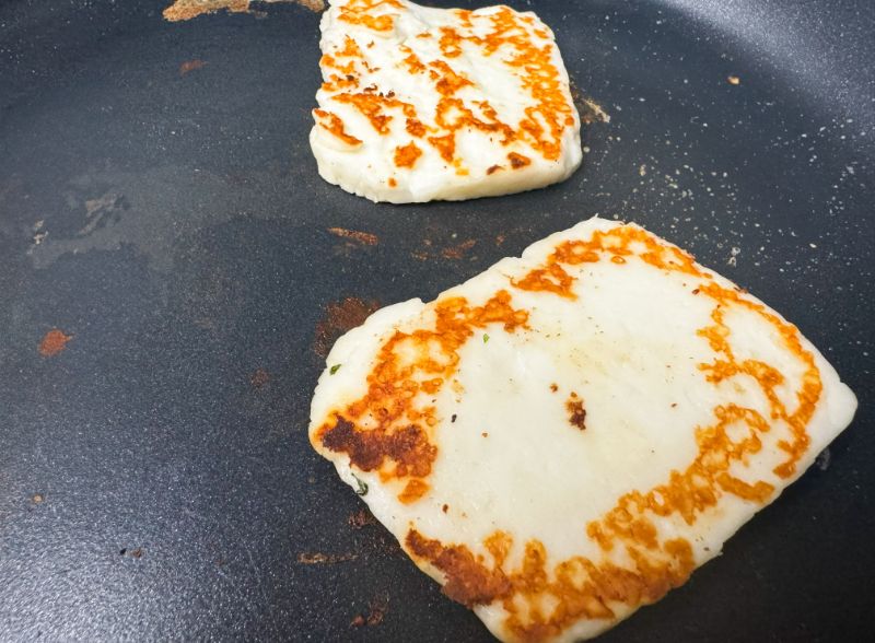 slices of halloumi cheese cooking in skillet.