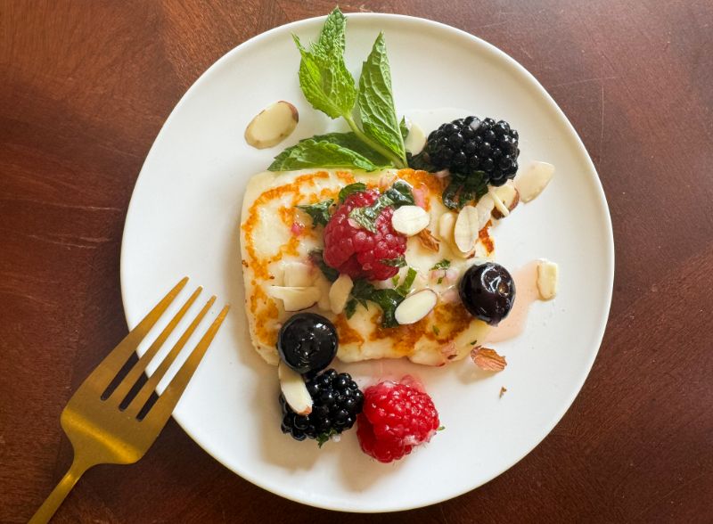 cooking halloumi cheese topped with vinaigrette and berries.