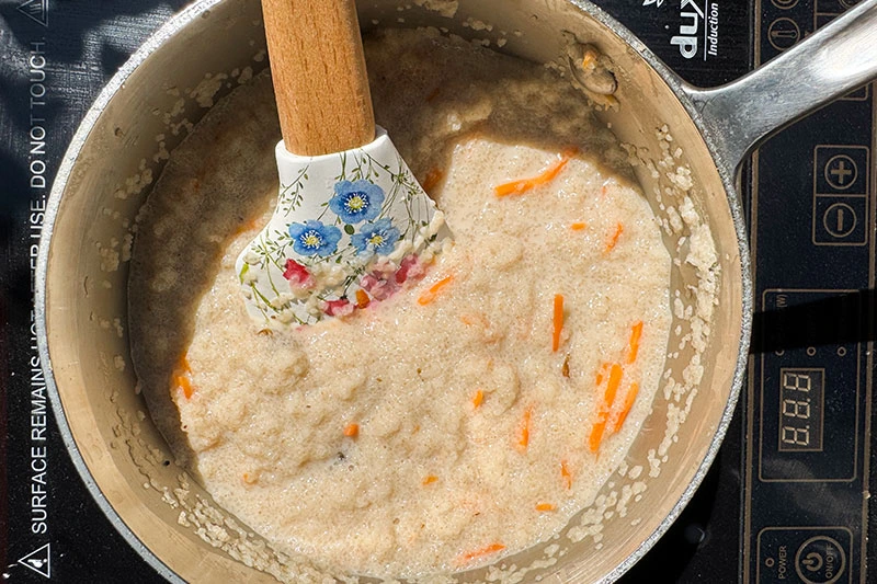 stirring fonio cereal in a pot.