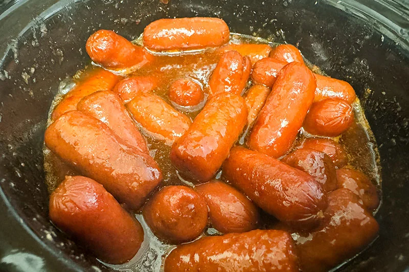 smokies and sauce in a crock pot cooking.