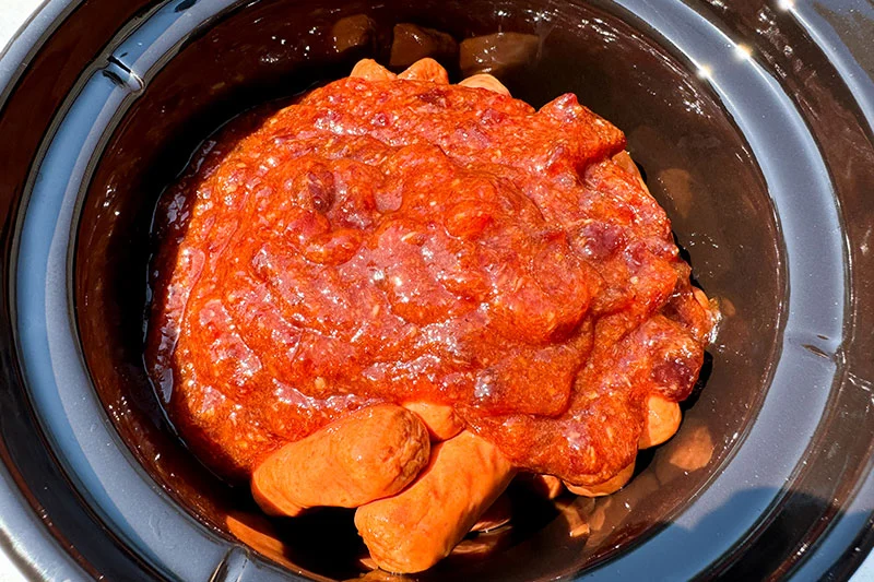 smokies topped with sauce in crock pot.