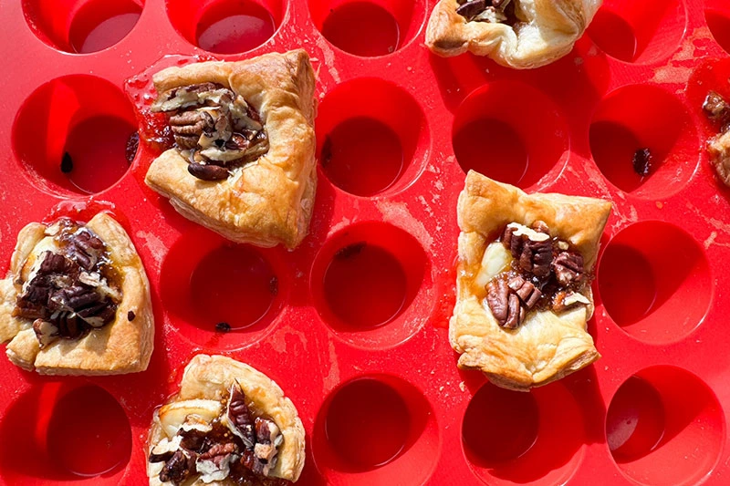 baked brie, fig and pecan puff pastry bites in muffin tray.