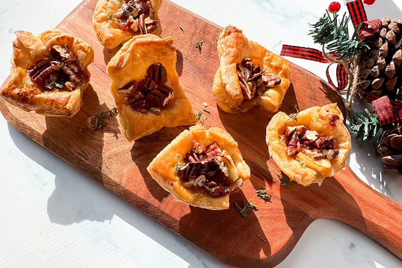 brie, fig and pecan puff pastry bites on a serving board.