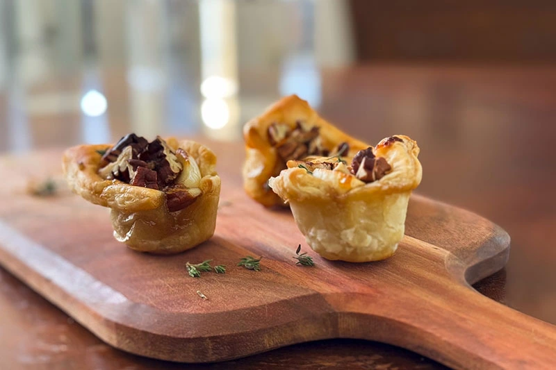 brie, fig and pecan puff pastry bites on a serving board.