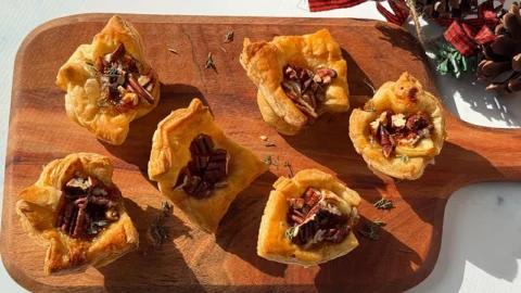 brie fig and pecan puff pastry bites on a serving board.