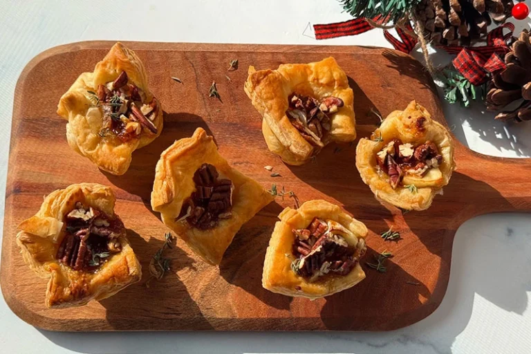 brie fig and pecan puff pastry bites on a serving board.