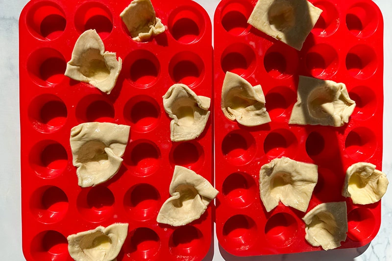 puff pastry squares in muffin trays.