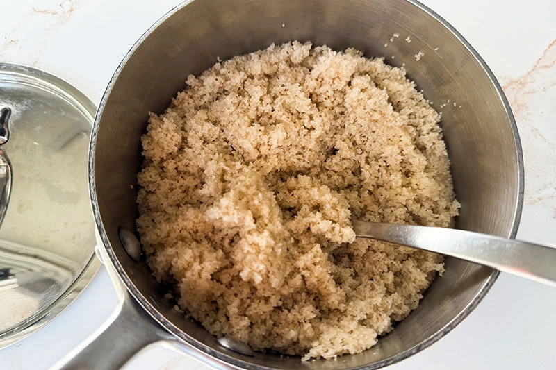 cooked fonio with fork in pot.