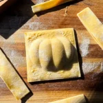 Pumpkin shaped ravioli on cutting board.