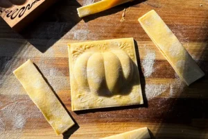 Pumpkin shaped ravioli on cutting board.