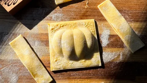 Pumpkin shaped ravioli on cutting board.