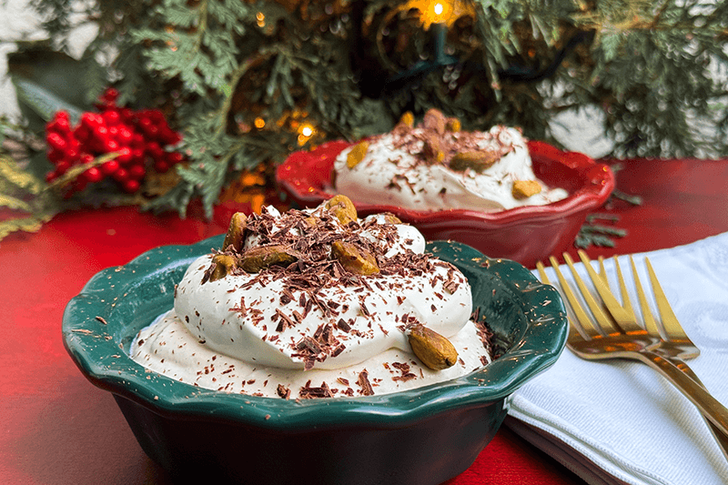 two cannoli pies garnished with whipped cream, chocolate and pistachios.