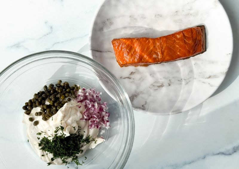 piece of salmon and bowl of other ingredients for spread.