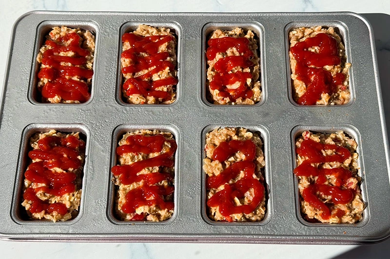 mini loaf pan filled with meatloaf and drizzled with ketchup.