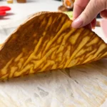 baked cottage cheese flatbread being held up.