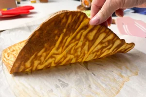 baked cottage cheese flatbread being held up.