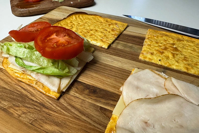 baked cottage cheese flatbread cut and being made into sandwiches.