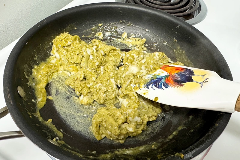 pesto eggs being scrambled in skillet.