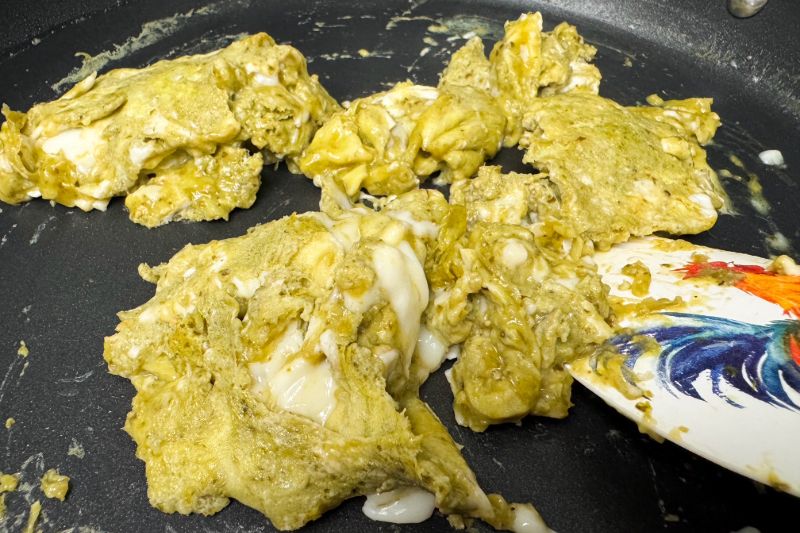 eggs and pesto scrambling in skillet.