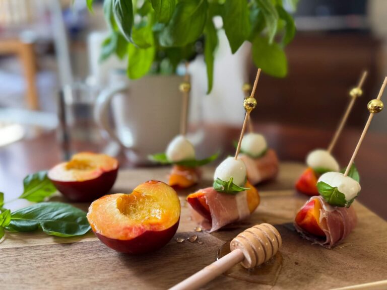 A wooden tray displaying an assortment of fresh fruit alongside a small jar of honey.
