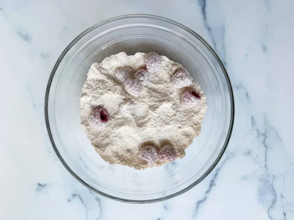 Raspberries tossed in white flour, a step in making white chocolate blonde brownies.