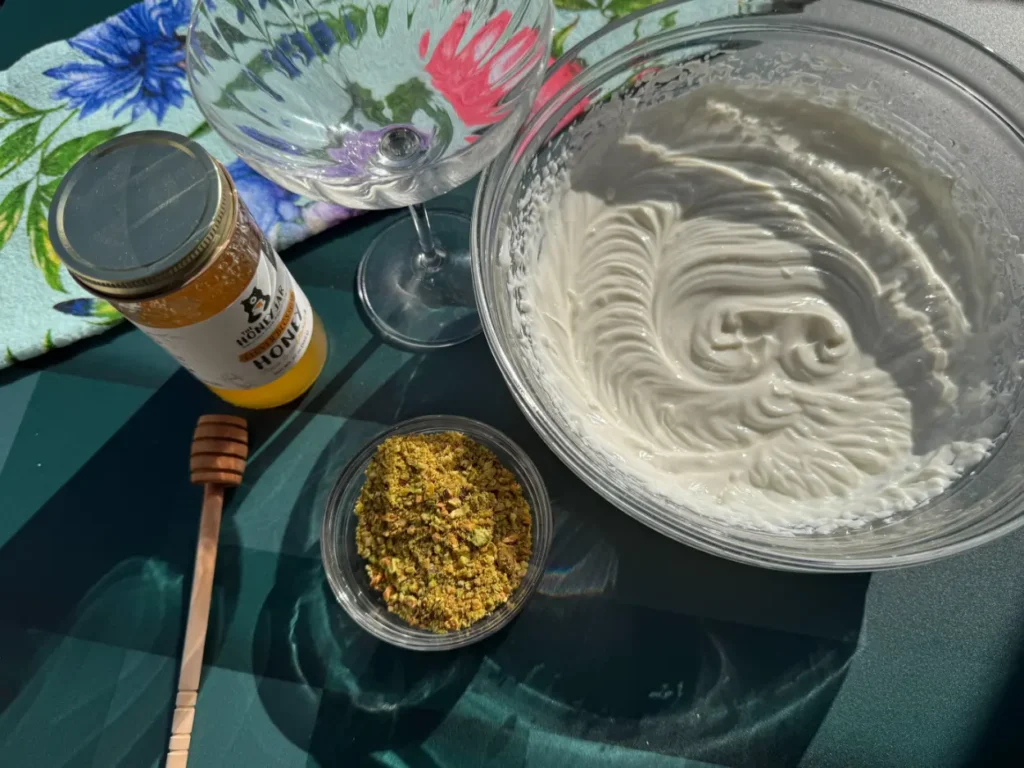 bowl of whipped cream, honey and chopped pistachios.
